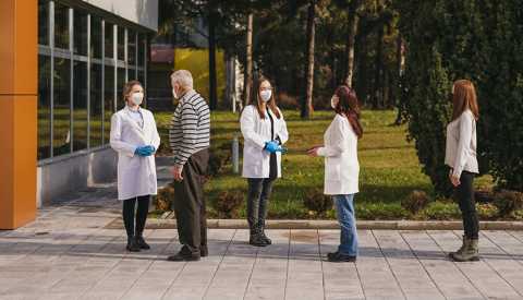 group of people waiting outdoors masked and distanced in a line to get the coronavirus vaccine